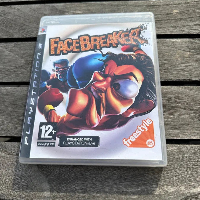 A PlayStation 3 game case for the video game Facebreaker, featuring a colorful boxing character illustration, resting on a weathered gray wooden plank surface.