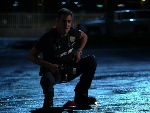 Person squatting on a street at night with a dark background