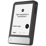 A portable Bitcoin signer device with a black frame and a silver metal base, featuring a screen that displays a transaction signing interface.