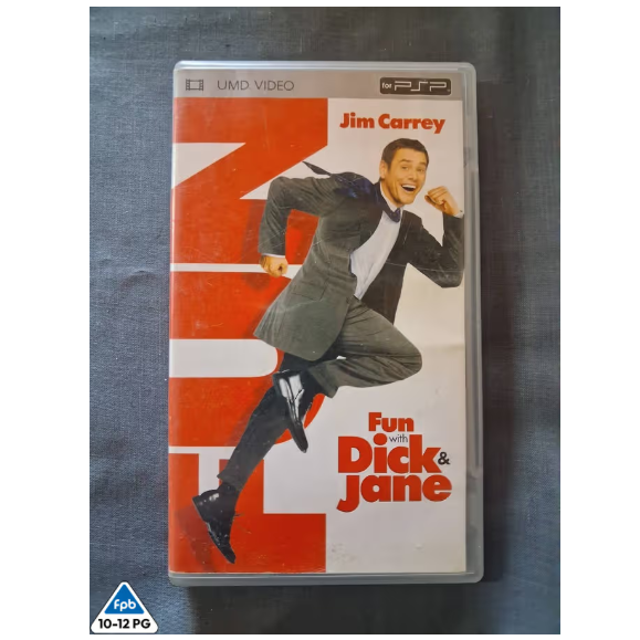 A PSP video game case for 'Fun Dick & Jane' starring Jim Carrey, resting on a dark gray fabric surface. The cover features a large orange and white graphic background with an illustration of Jim Carrey in a suit.