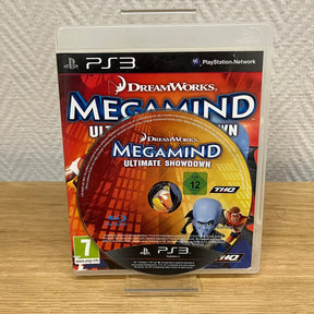 PS3 video game case for DreamWorks Megamind Ultimate Showdown, displayed upright on a small clear stand on a wooden surface against a textured white wall.