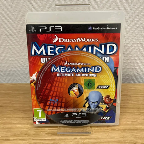PS3 video game case for DreamWorks Megamind Ultimate Showdown, displayed upright on a small clear stand on a wooden surface against a textured white wall.