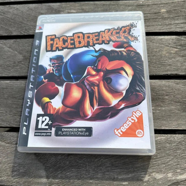 A PlayStation 3 game case for the video game Facebreaker, featuring a colorful boxing character illustration, resting on a weathered gray wooden plank surface.