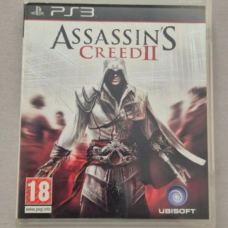 Assassin's Creed II video game for PlayStation 3 in a clear plastic case, showing the character Ezio with the Ubisoft and PEGI 18 logos on the cover, photographed on a neutral gray background.