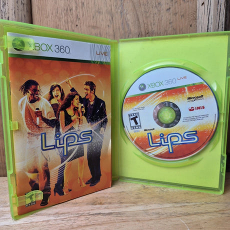 Xbox 360 'Lips' video game case shown open with the game disc inside a translucent neon green plastic case, placed on a wooden surface.