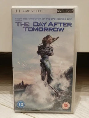 A PSP UMD video case for the movie 'The Day After Tomorrow' sitting on a light-colored wooden surface. The cover art features a dramatic illustration of the Statue of Liberty rising from turbulent water under a pale sky.
